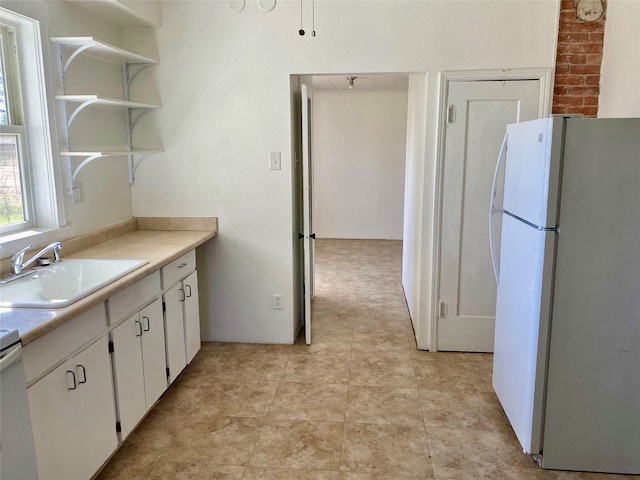 kitchen featuring light tile flooring, sink, white refrigerator, and white cabinets