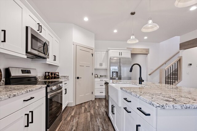 kitchen featuring dark hardwood / wood-style floors, white cabinetry, stainless steel appliances, and a center island with sink