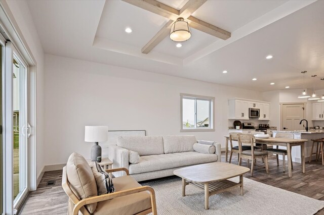 living room featuring coffered ceiling, dark hardwood / wood-style floors, beamed ceiling, and sink