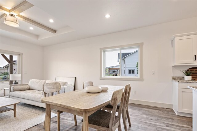 dining space with light hardwood / wood-style flooring and beam ceiling