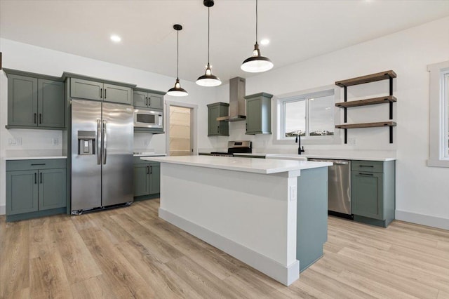 kitchen with stainless steel appliances, sink, wall chimney range hood, decorative light fixtures, and light hardwood / wood-style flooring