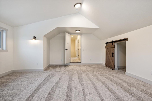 bonus room featuring carpet flooring, a barn door, and vaulted ceiling