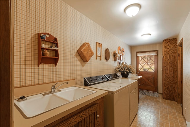 laundry area featuring washing machine and clothes dryer, cabinets, and sink