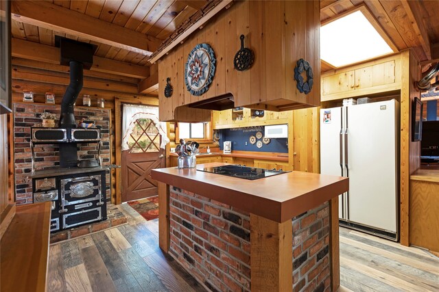 kitchen featuring white refrigerator, light hardwood / wood-style flooring, a wood stove, and black electric stovetop