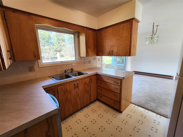 kitchen with brown cabinetry, light countertops, a sink, and decorative light fixtures