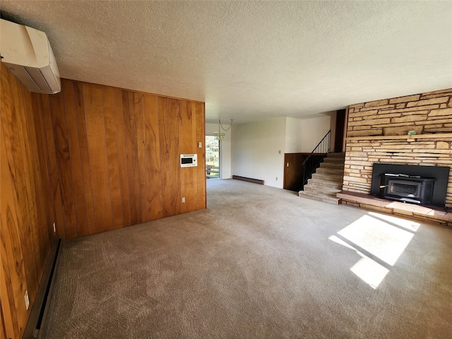 unfurnished living room with a textured ceiling, a wall mounted air conditioner, wood walls, stairway, and carpet