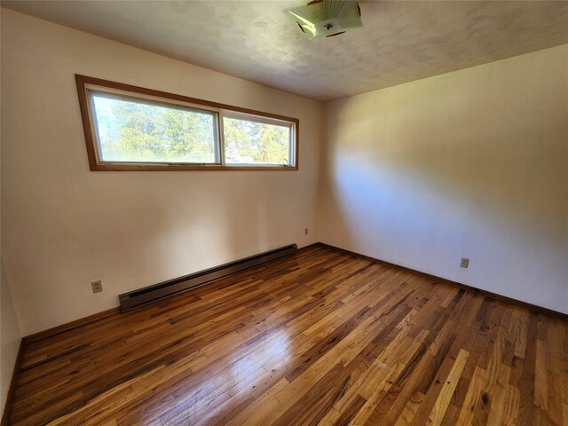 empty room with dark wood-style flooring and baseboard heating