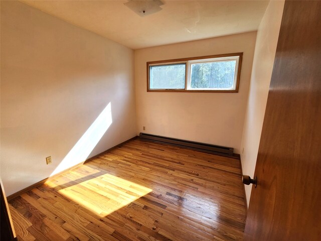 empty room with a baseboard radiator and wood finished floors