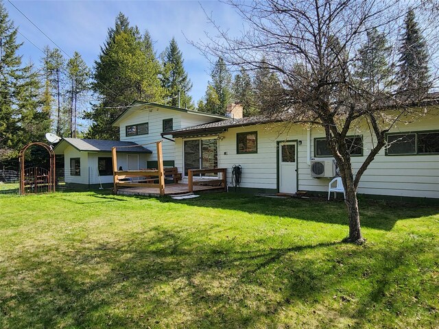 rear view of property with a lawn, a chimney, and a wooden deck