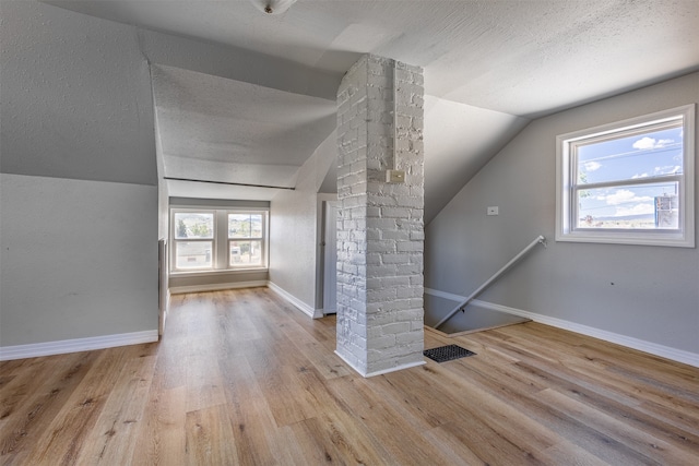 bonus room with a textured ceiling, decorative columns, lofted ceiling, and light wood-type flooring