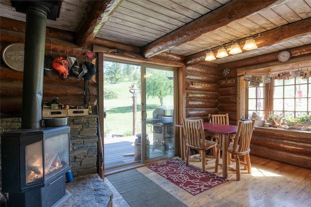 dining area featuring wood ceiling, a wealth of natural light, a wood stove, and rustic walls