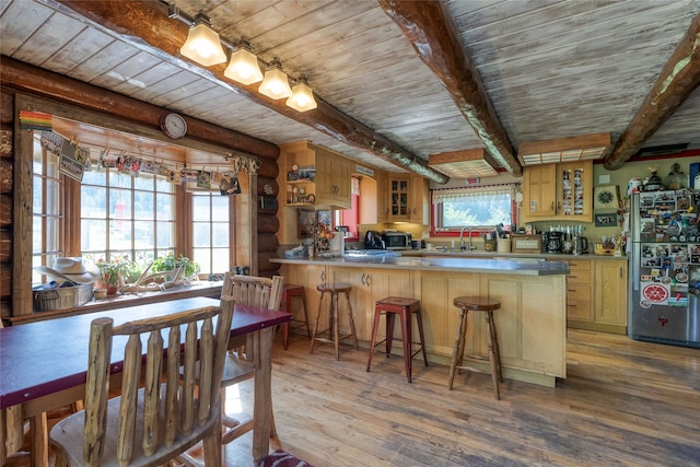 kitchen featuring kitchen peninsula, a kitchen bar, beam ceiling, stainless steel fridge, and wooden ceiling