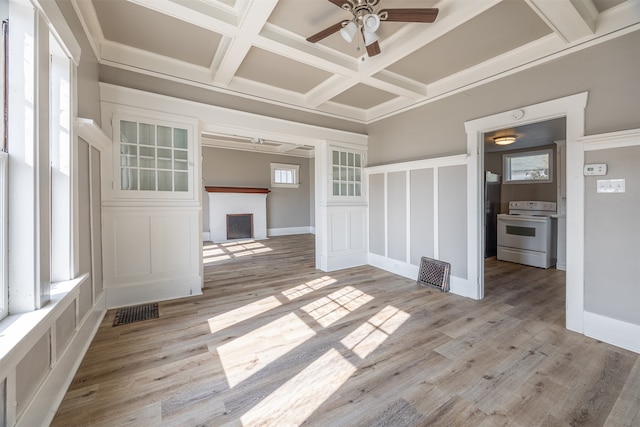 unfurnished living room with ceiling fan, coffered ceiling, plenty of natural light, and light hardwood / wood-style floors