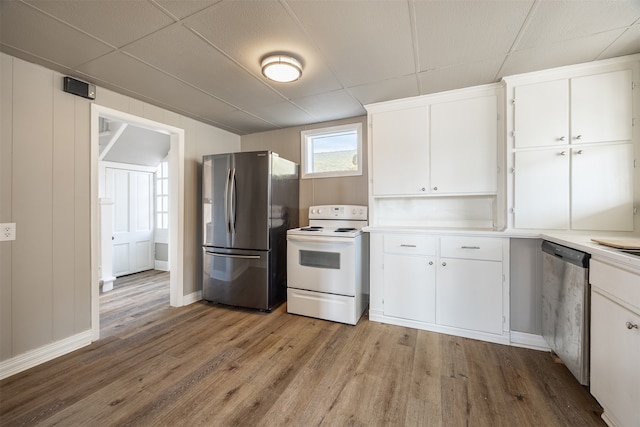 kitchen with light hardwood / wood-style flooring, appliances with stainless steel finishes, a drop ceiling, and white cabinetry