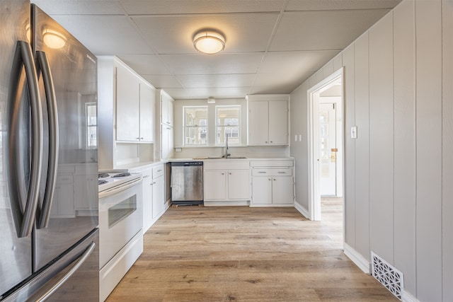 kitchen featuring stainless steel appliances, white cabinets, sink, and light wood-type flooring