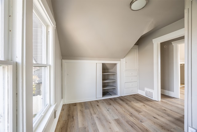 additional living space with vaulted ceiling and light hardwood / wood-style flooring