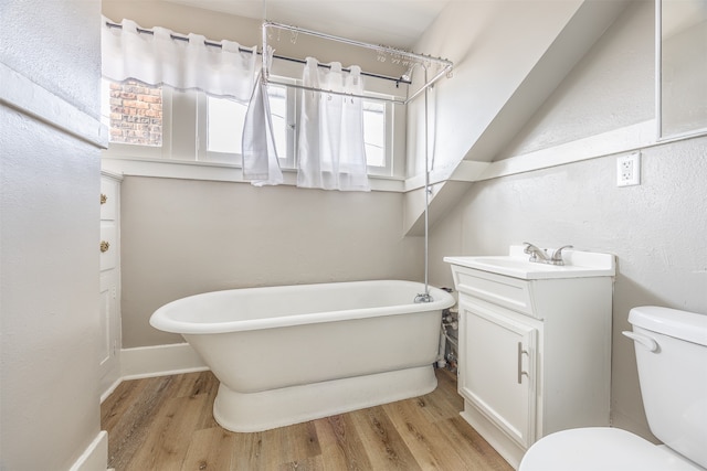 bathroom with wood-type flooring, a tub to relax in, vanity, and toilet