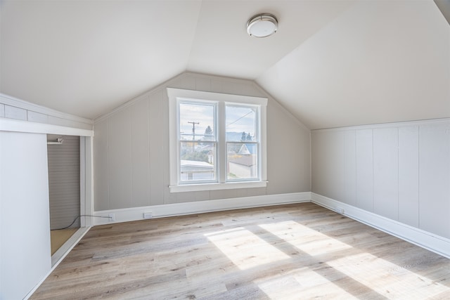 bonus room with light wood-type flooring and vaulted ceiling