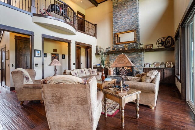 living room featuring wood-type flooring, a towering ceiling, and a fireplace