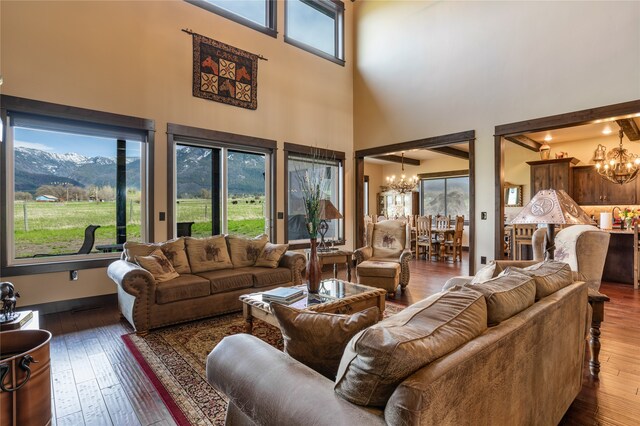 living room with dark hardwood / wood-style floors, a towering ceiling, a mountain view, and a chandelier