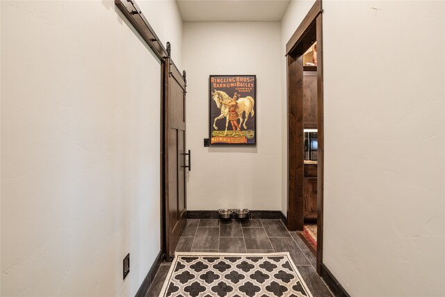 hallway with dark tile floors and a barn door