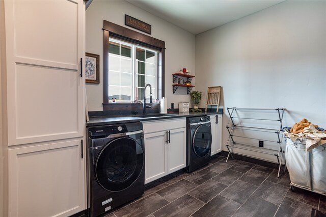 washroom featuring washing machine and clothes dryer, dark tile flooring, cabinets, and sink