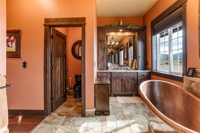 bathroom with a washtub, an inviting chandelier, tile flooring, and vanity