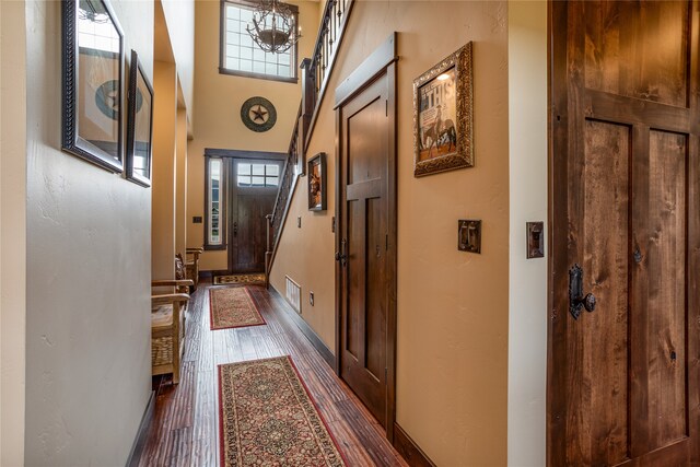 hallway with a healthy amount of sunlight, dark wood-type flooring, and a high ceiling