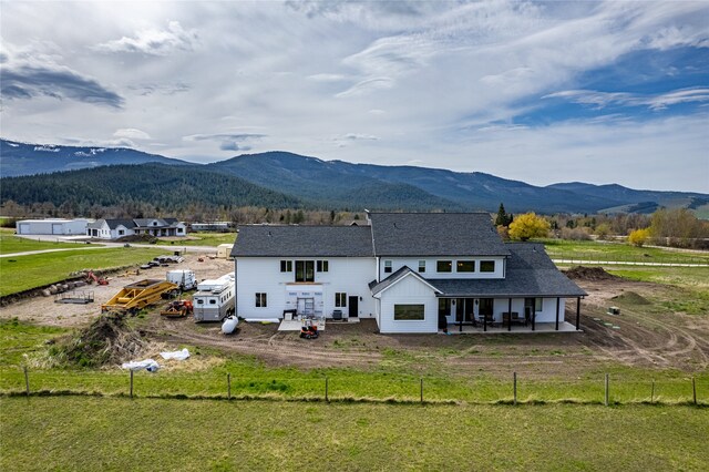 back of property with a mountain view and a lawn