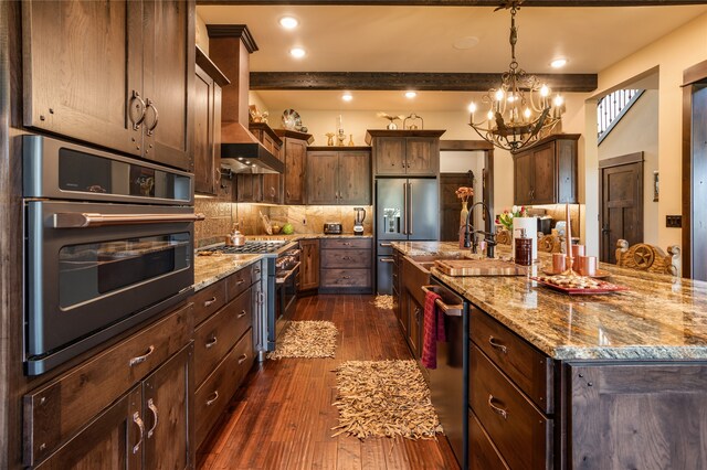 kitchen featuring custom exhaust hood, high quality appliances, backsplash, dark wood-type flooring, and a kitchen island with sink