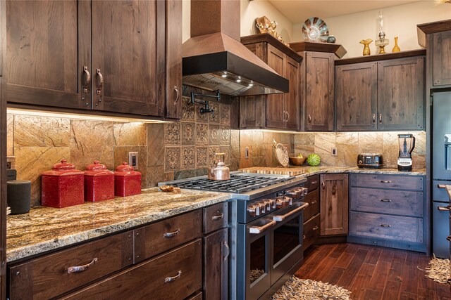 kitchen featuring range with two ovens, backsplash, dark hardwood / wood-style floors, wall chimney exhaust hood, and light stone counters