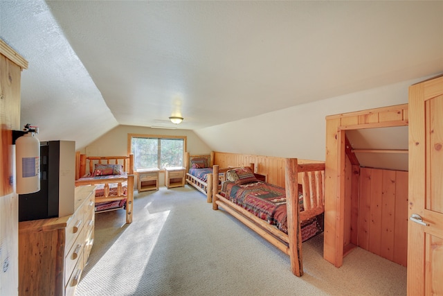 carpeted bedroom featuring lofted ceiling, a textured ceiling, and wooden walls