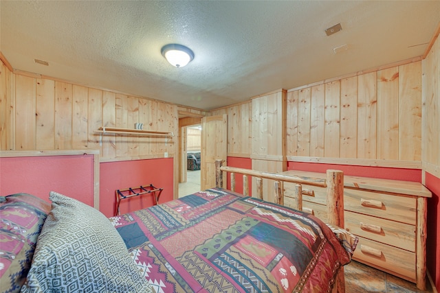 bedroom featuring a textured ceiling and wooden walls