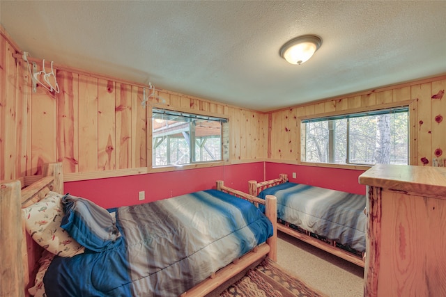 bedroom with wood walls, carpet flooring, and a textured ceiling