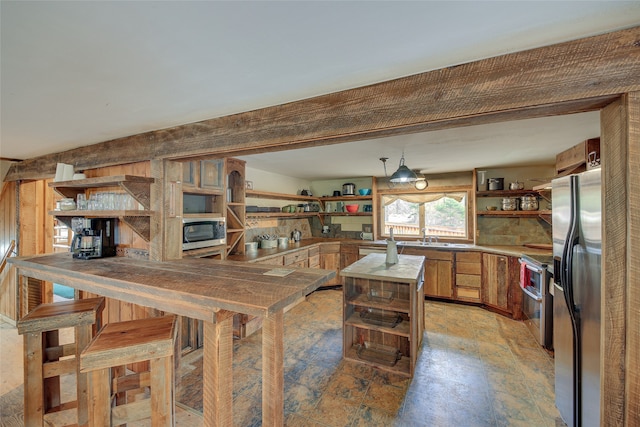 kitchen featuring hanging light fixtures, sink, stainless steel appliances, and kitchen peninsula