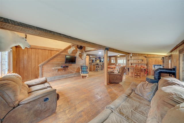 living room with hardwood / wood-style flooring, wood walls, a healthy amount of sunlight, and beam ceiling