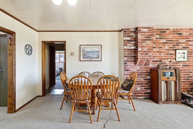 carpeted dining space with brick wall and ornamental molding