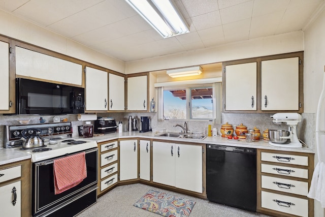 kitchen with tasteful backsplash, white cabinets, black appliances, and sink