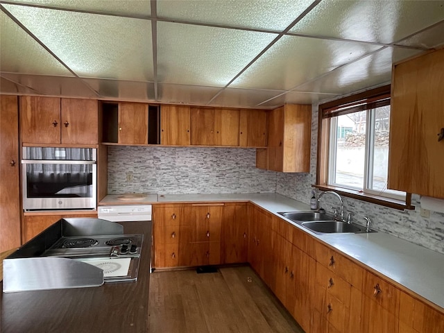 kitchen featuring stainless steel oven, sink, dark wood-type flooring, cooktop, and a paneled ceiling