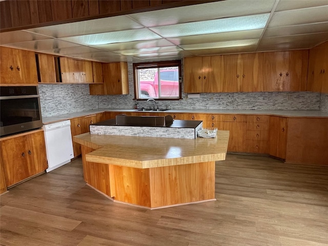 kitchen with a center island, a paneled ceiling, white dishwasher, and stainless steel oven