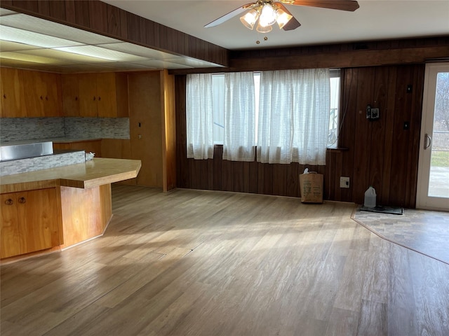 kitchen featuring a kitchen bar, wooden walls, ceiling fan, and light wood-type flooring