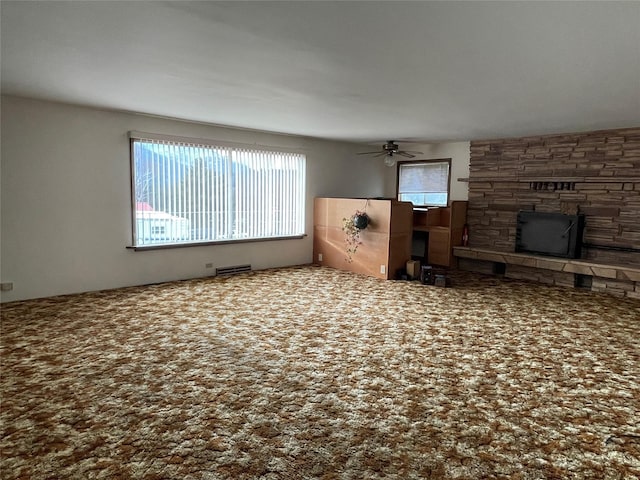 unfurnished living room featuring carpet floors, a stone fireplace, and ceiling fan