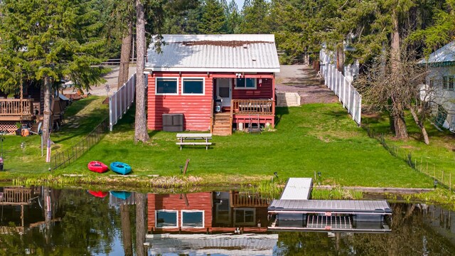 rear view of house with a deck with water view and a lawn