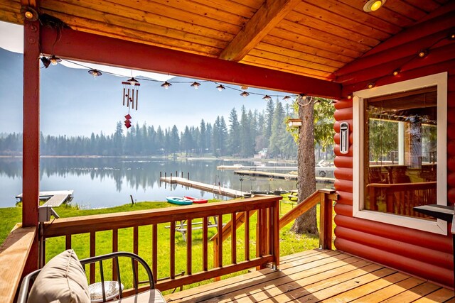 wooden deck with a water view and a lawn