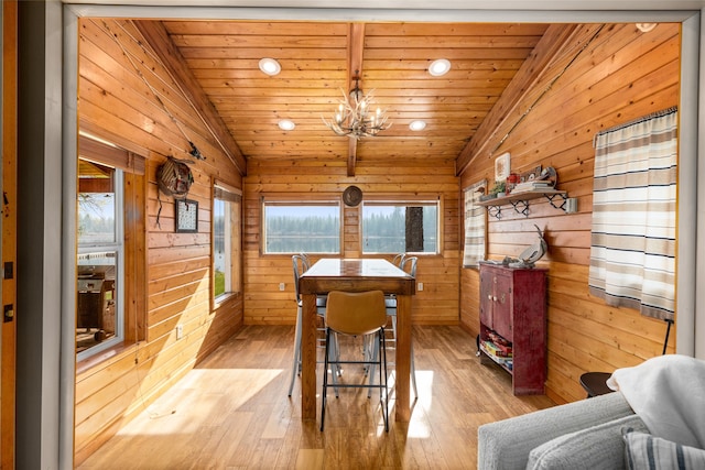 dining area with vaulted ceiling, light hardwood / wood-style flooring, wooden ceiling, wooden walls, and a notable chandelier