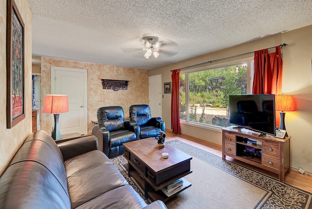 living room with hardwood / wood-style floors, ceiling fan, and a textured ceiling