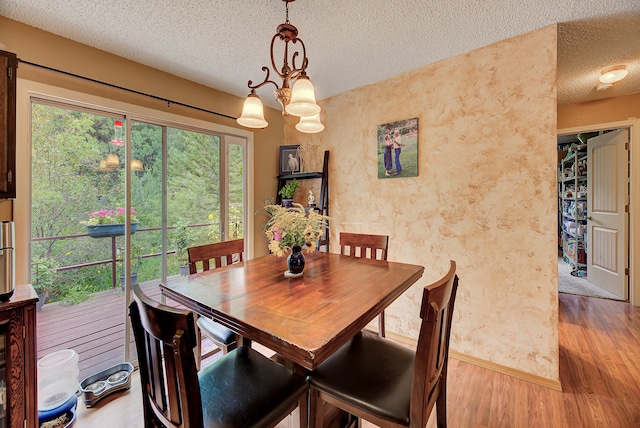 dining area featuring wood-type flooring and a textured ceiling