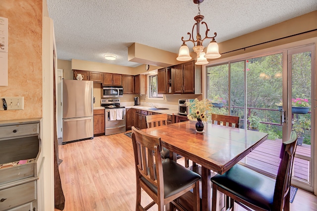 dining room with a notable chandelier, light hardwood / wood-style floors, and a textured ceiling