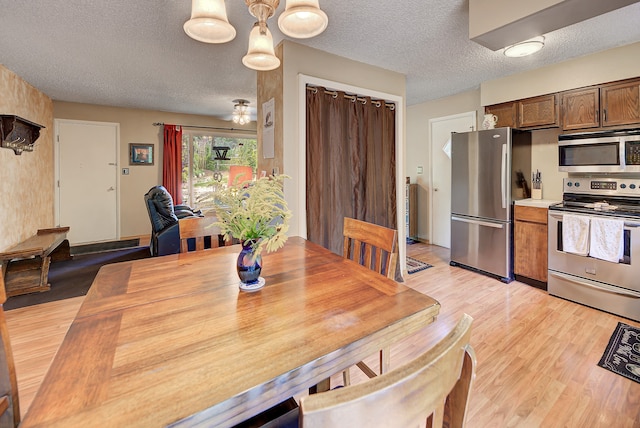 dining area with light hardwood / wood-style flooring and a textured ceiling