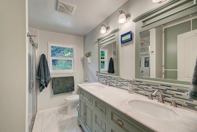 bathroom with tile floors, backsplash, toilet, and dual bowl vanity